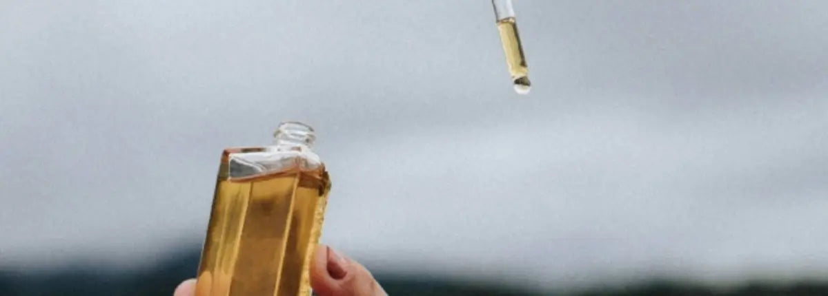Goutte d’huile essentielle tombant d’une pipette pour un soin nourrissant dédié aux cheveux bouclés